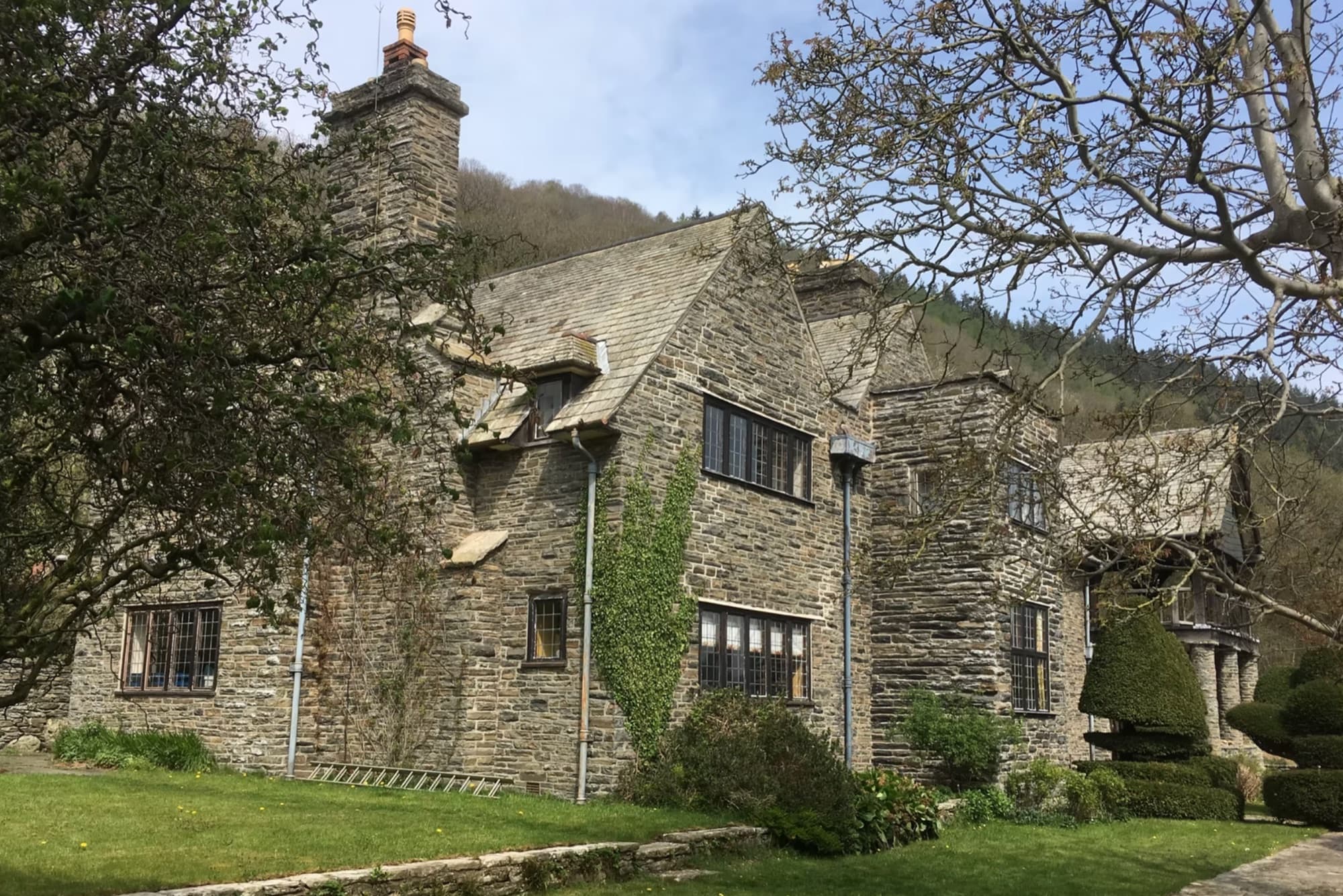 The hall's stone frontage among spring trees