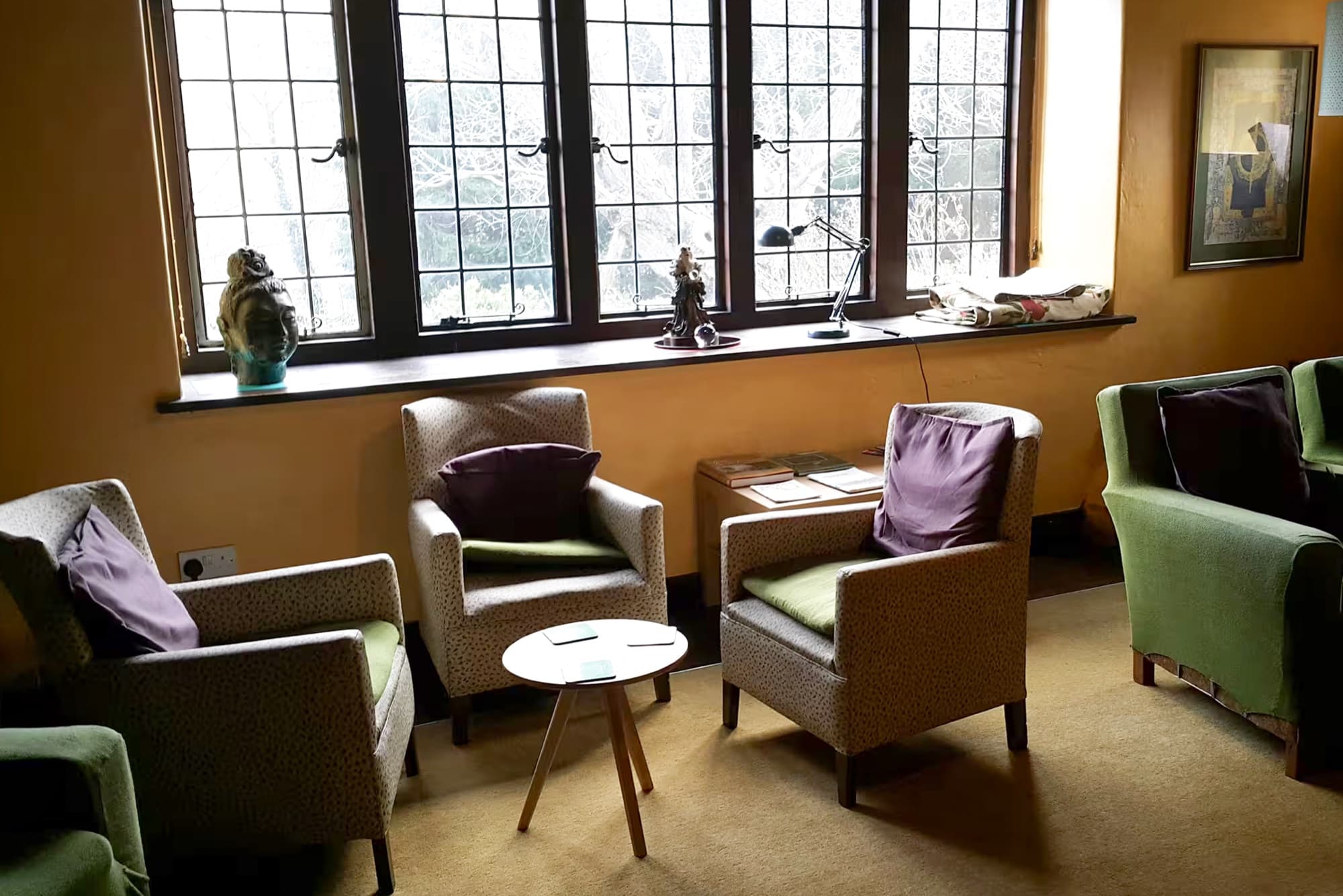 A sitting room with armchairs beneath tall leaded windows