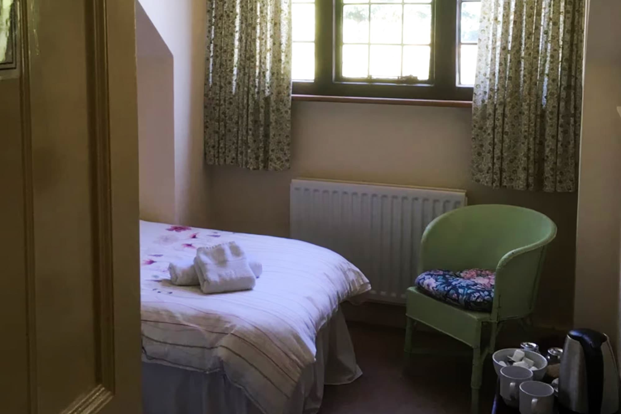 A single bedroom with a green wicker chair by the window