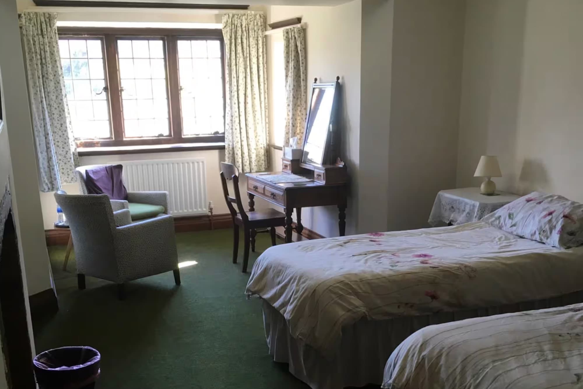 A twin bedroom with a dressing table under a leaded window