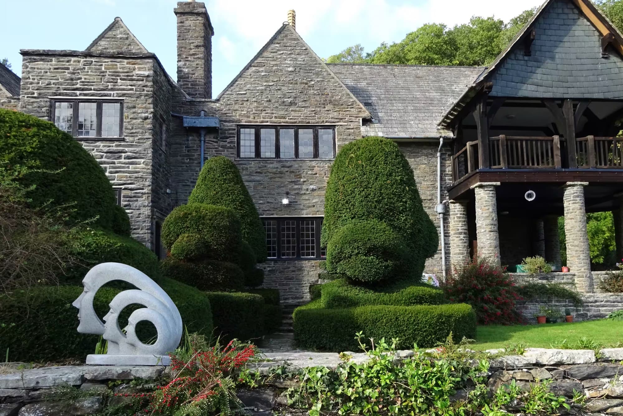 A white stone sculpture in front of the hall's topiary garden