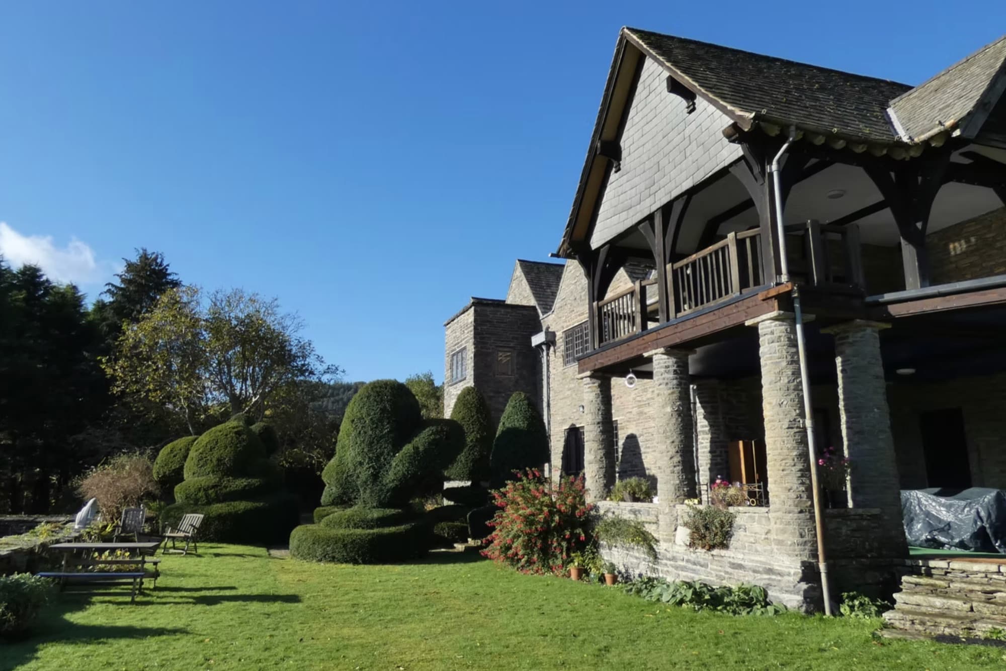 The hall's timber veranda and topiary lawn on a sunny day